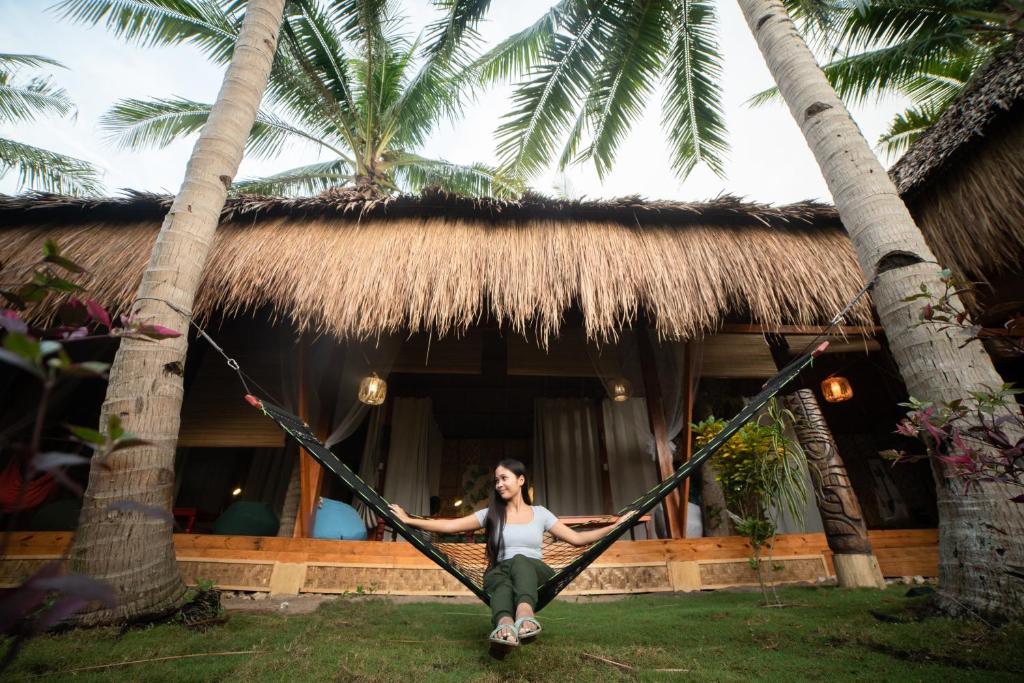 a woman in a hammock in front of a house at Nautilus Hostel & Hammocks in Panglao Island