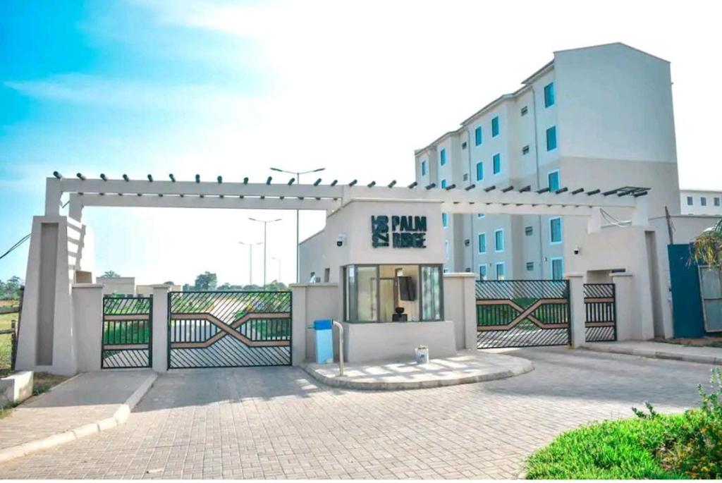 a white building with a gate and a fence at 1255 Palm Ridge Vipingo Estate Apartments in Kilifi