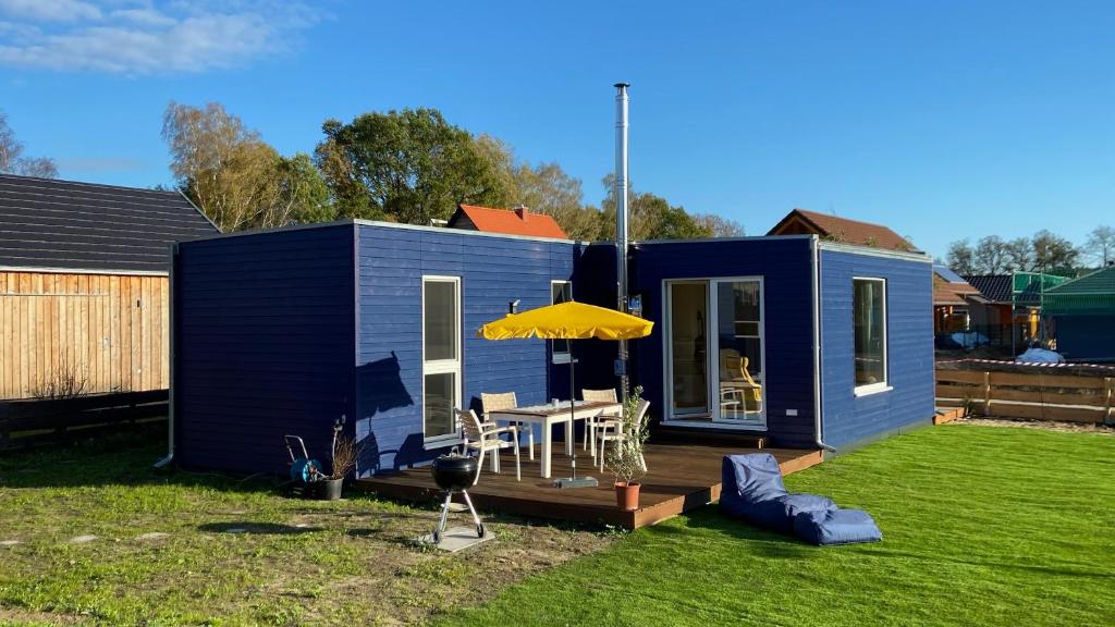 uma pequena casa azul com uma mesa e um guarda-chuva em Tiny House mit Sauna am See em Repente