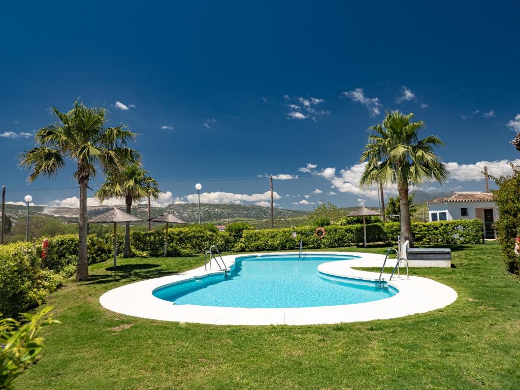 einen Pool in einem Garten mit Palmen in der Unterkunft Lotus 2401 - Beautiful apartment with pool & sea view in Casares