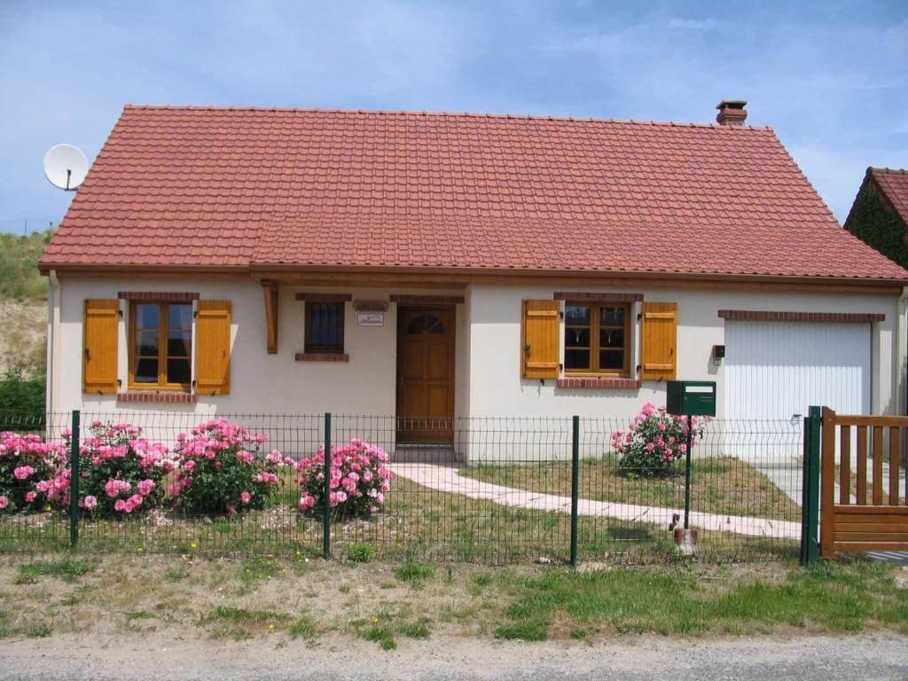 una pequeña casa blanca con techo rojo y flores rosas en Maison Fort-Mahon-Plage, 4 pièces, 6 personnes - FR-1-482-43, en Fort-Mahon-Plage