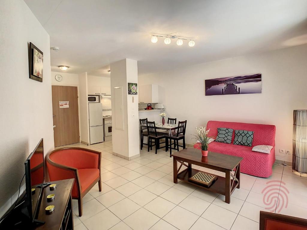 un salon avec un canapé rouge et une table dans l'établissement Appartement F2 Climatisé avec Terrasse et Parking à 700m des Thermes de Lamalou Les Bains - FR-1-451-121, à Lamalou-les-Bains