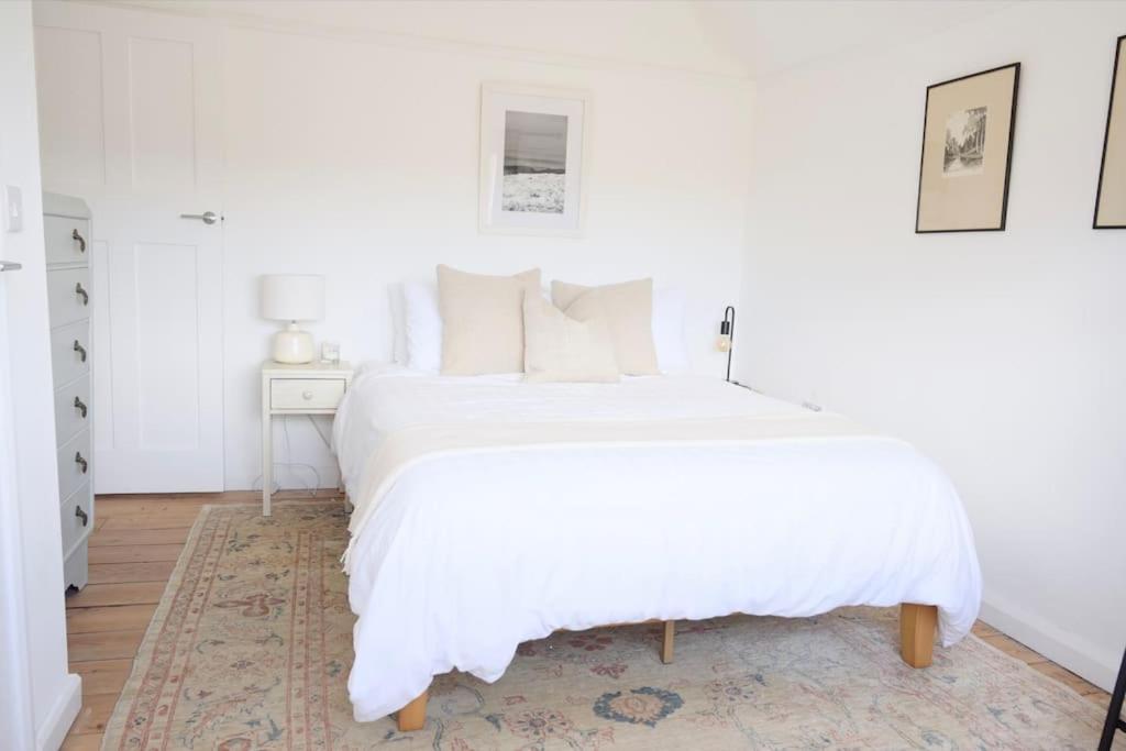 a white bedroom with a white bed and a table at The Palm House Falmouth - minutes from the beach! in Falmouth