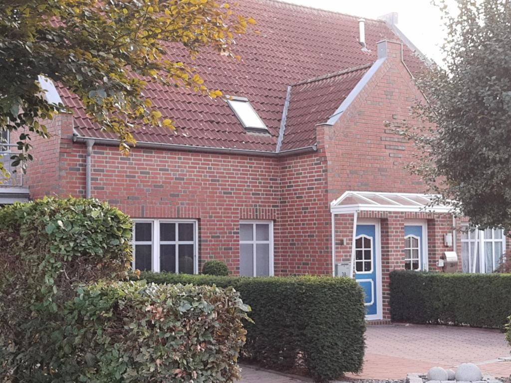 a red brick house with a blue door at Ferienwohnung Zweite Heimat 45248 in Ditzum