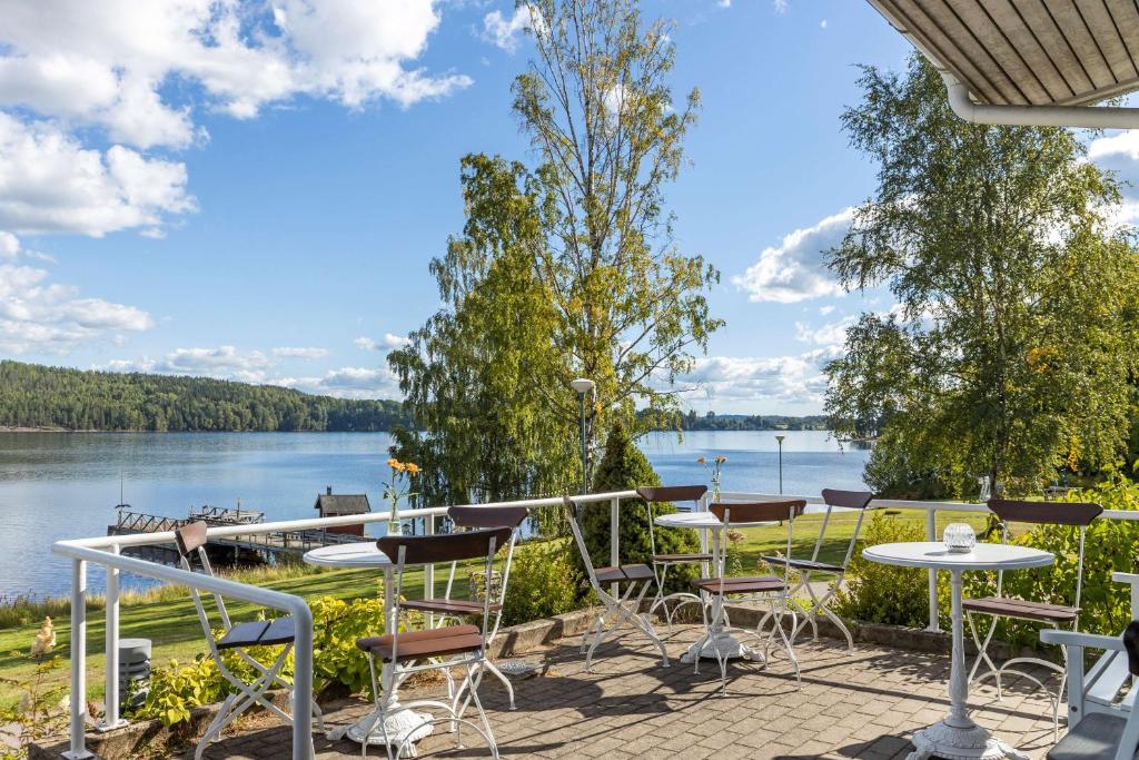 a patio with tables and chairs and a view of a lake at Hotell Frykenstrand; Sure Hotel Collection by Best Western in Sunne