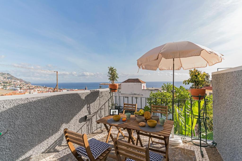 einen Tisch und Stühle mit Sonnenschirm auf dem Balkon in der Unterkunft Arrifes I by An Island Apart in Funchal