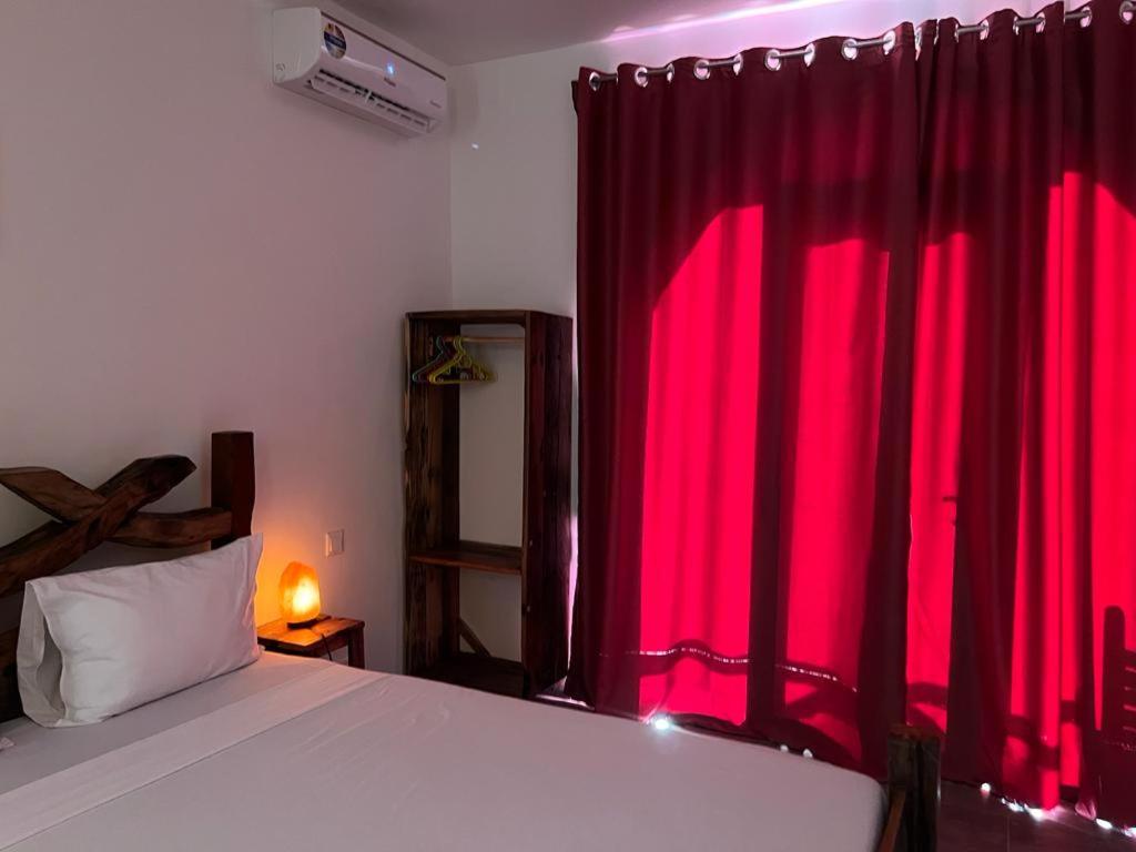 ケンドワにあるLala salama Kendwa villasの赤いカーテン付きのベッドルーム1室、窓の前にベッド1台が備わります。