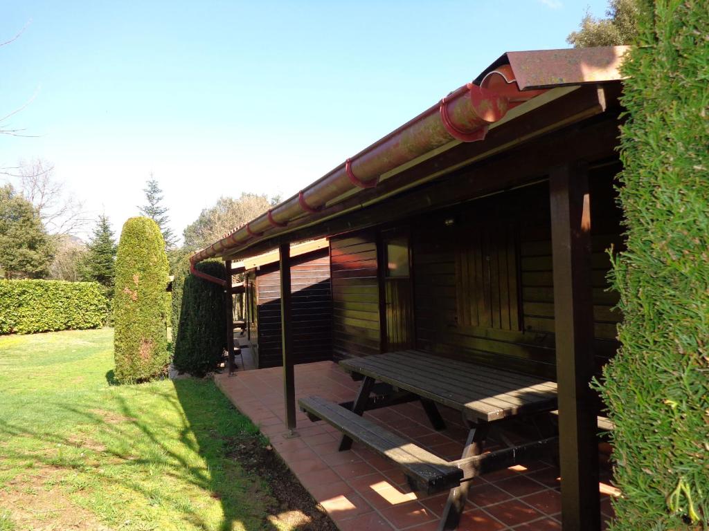 a wooden cabin with a picnic bench on a patio at Camping Lava in Santa Pau