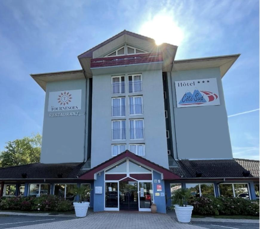 a hotel front with the sun in the sky at Hôtel Côté Sud Léman in Thonon-les-Bains