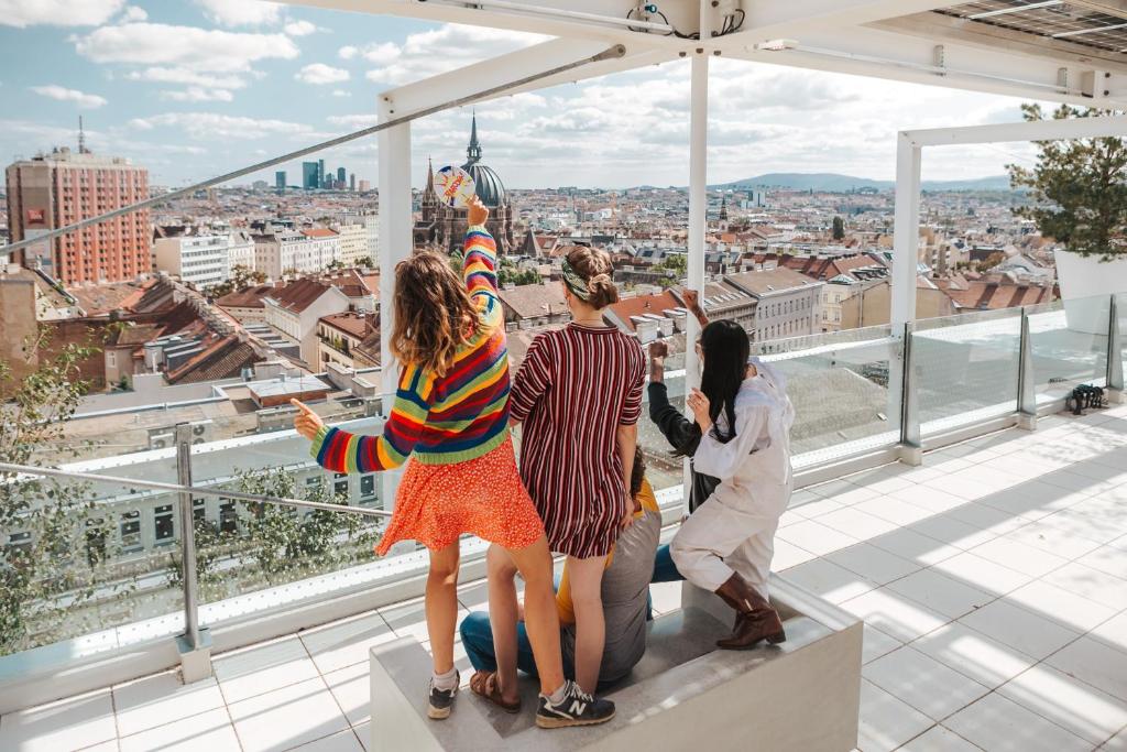 a group of girls standing on a roof looking at a city at JO&JOE Vienna in Vienna