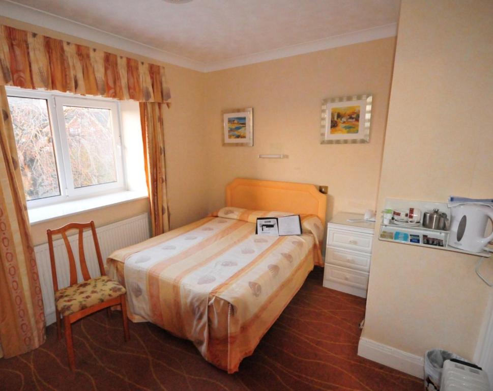 Dormitorio pequeño con cama y nevera en Devoncourt Short Term Rentals, en Exmouth