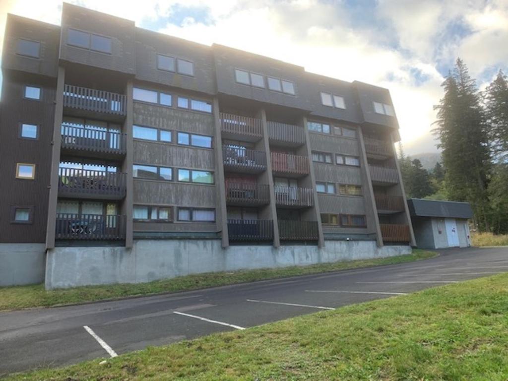 un parking vide devant un bâtiment dans l'établissement Appartement Mont-Dore, 2 pièces, 4 personnes - FR-1-415-64, à Le Mont-Dore