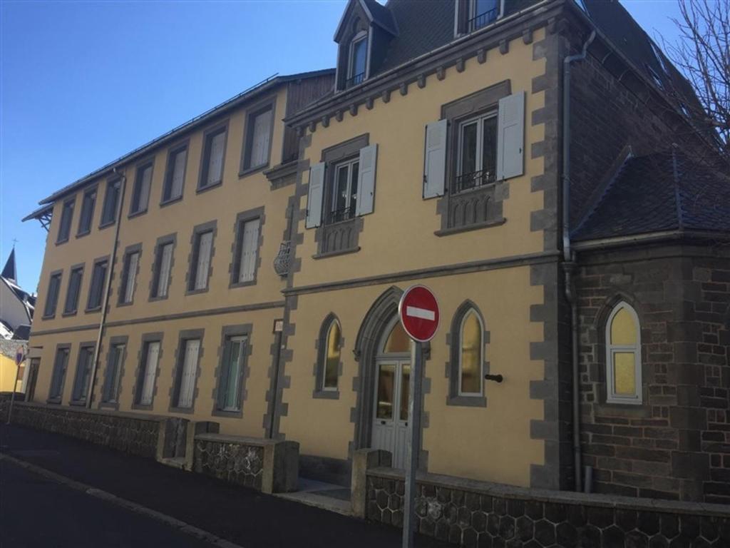 un bâtiment jaune avec un panneau d'arrêt devant lui dans l'établissement Appartement Mont-Dore, 3 pièces, 6 personnes - FR-1-415-69, à Le Mont-Dore