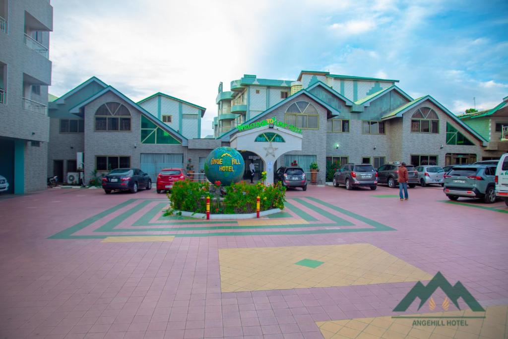 ein großes Gebäude mit Autos auf einem Parkplatz in der Unterkunft Ange Hill Hotel in Accra