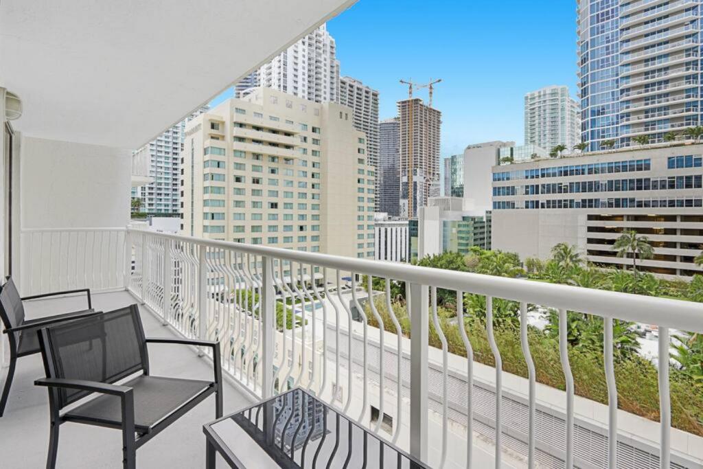 a balcony with a chair and a table and a city at Deluxe 1 BR suite with Pool, Parking, Balcony and Ocean Views in Miami