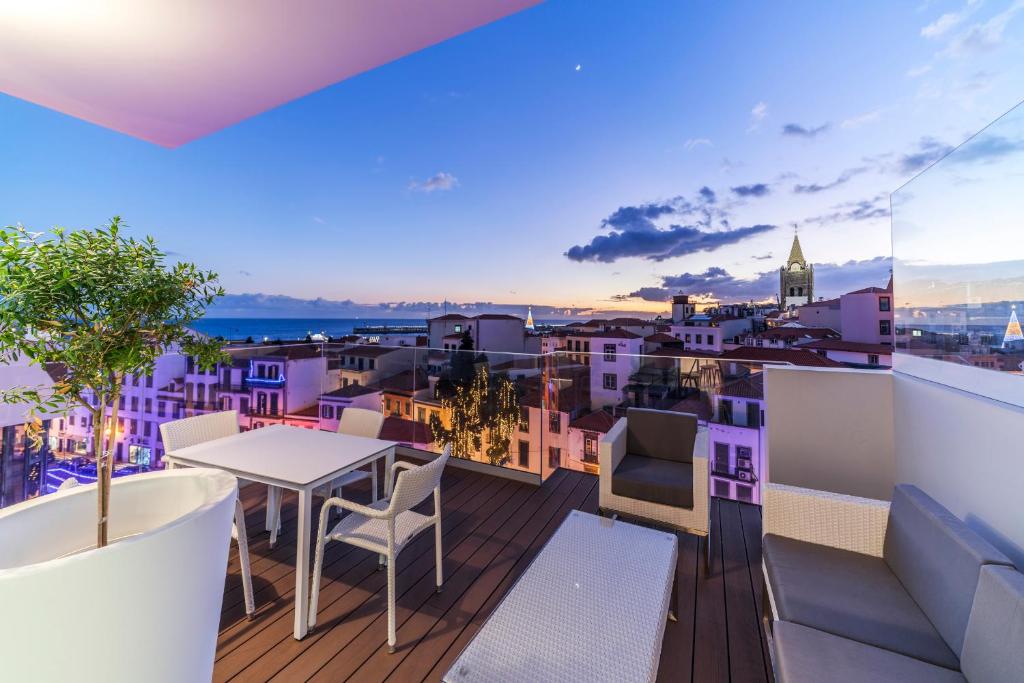 balcón con mesa, sillas y ciudad en FAA Rentals 31 de Janeiro by An Island Apart en Funchal