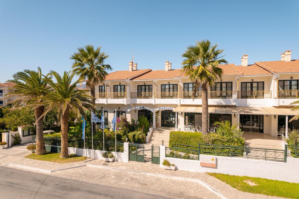 a large building with palm trees in front of it at Hydrele Beach Hotel & Village in Potokáki