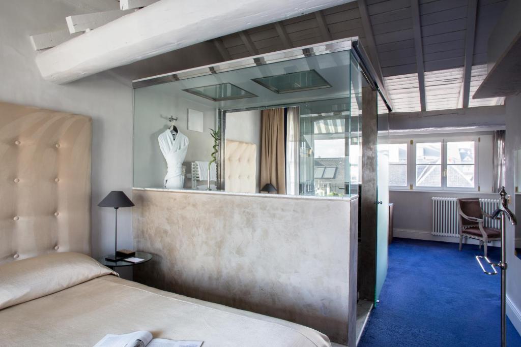 a bedroom with a bed and a mirror on the wall at Hotel Le Place d'Armes - Relais & Châteaux in Luxembourg
