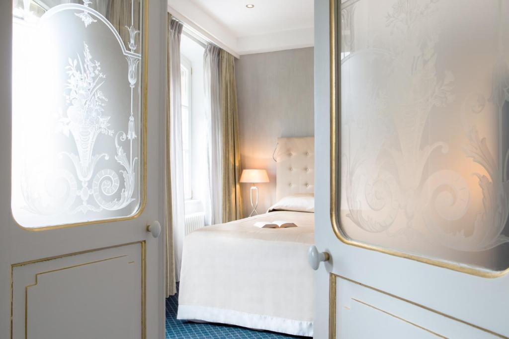 a bedroom with a bed and a door with a mirror at Hotel Le Place d'Armes - Relais & Châteaux in Luxembourg