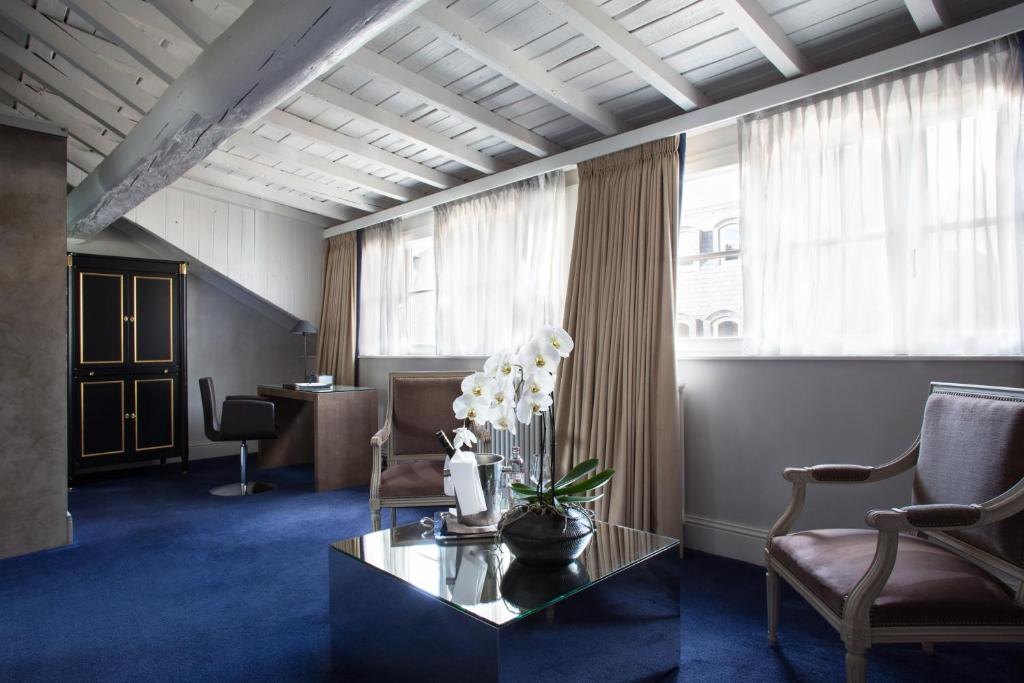 a waiting room with a table and chairs and windows at Hotel Le Place d'Armes - Relais & Châteaux in Luxembourg