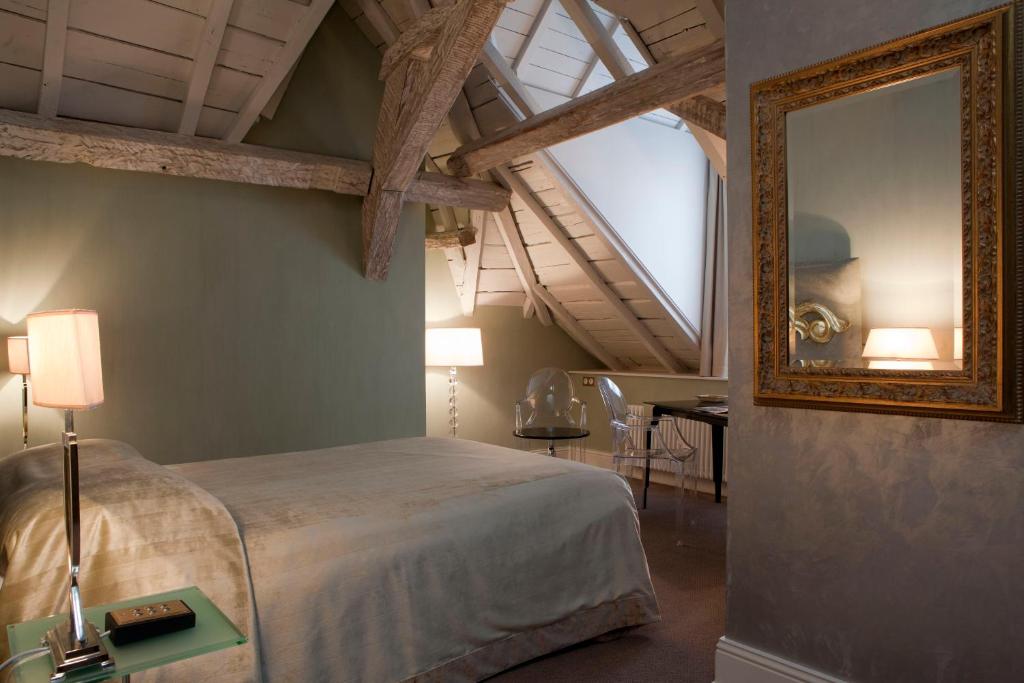a bedroom with a large bed and a mirror at Hotel Le Place d'Armes - Relais & Châteaux in Luxembourg