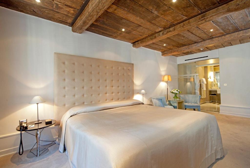 a bedroom with a large white bed with a wooden ceiling at Hotel Le Place d'Armes - Relais & Châteaux in Luxembourg
