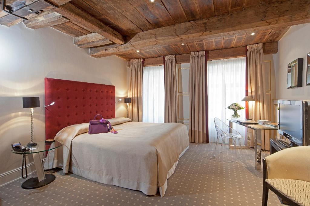 a bedroom with a large bed with a red headboard at Hotel Le Place d'Armes - Relais & Châteaux in Luxembourg