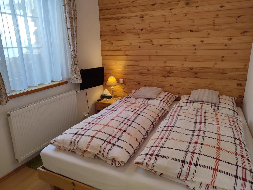 a bedroom with two beds and a wooden wall at Apartmán FuFu in Prostřední Lánov