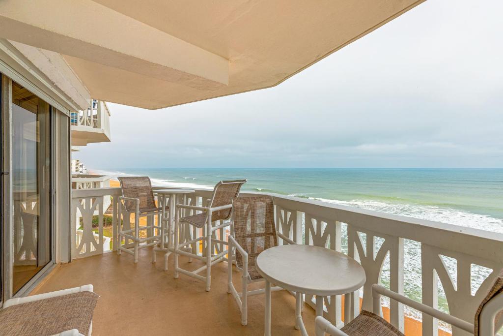 a balcony with chairs and tables and the ocean at Van Lee 1003 in Ormond Beach