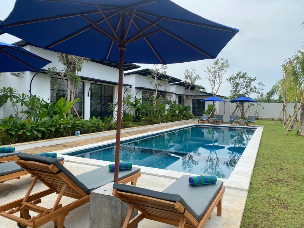 - une piscine avec 2 chaises et un parasol bleu dans l'établissement IBI bali, à Banjar