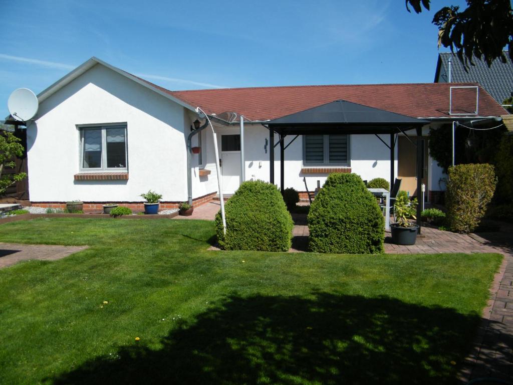 a white house with a black umbrella in a yard at Ferienbungalow Meerjungfrau im Seebad Ueckermünde in Ueckermünde