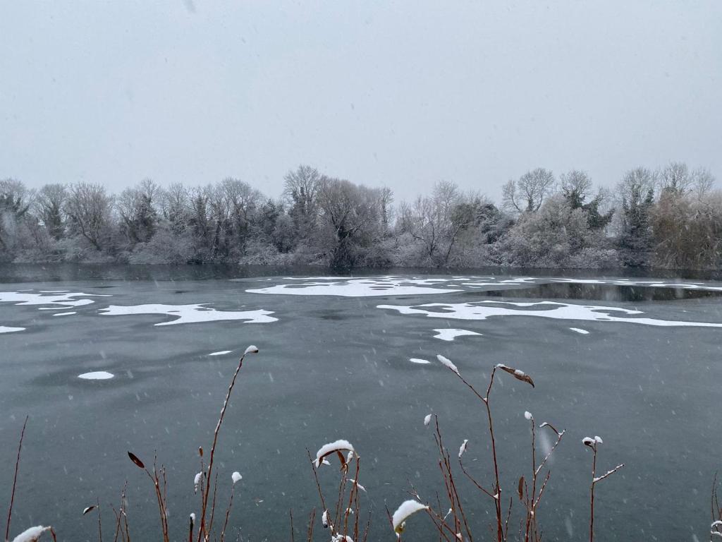 a frozen lake with snow on top of it at Herons Hideout in South Cerney