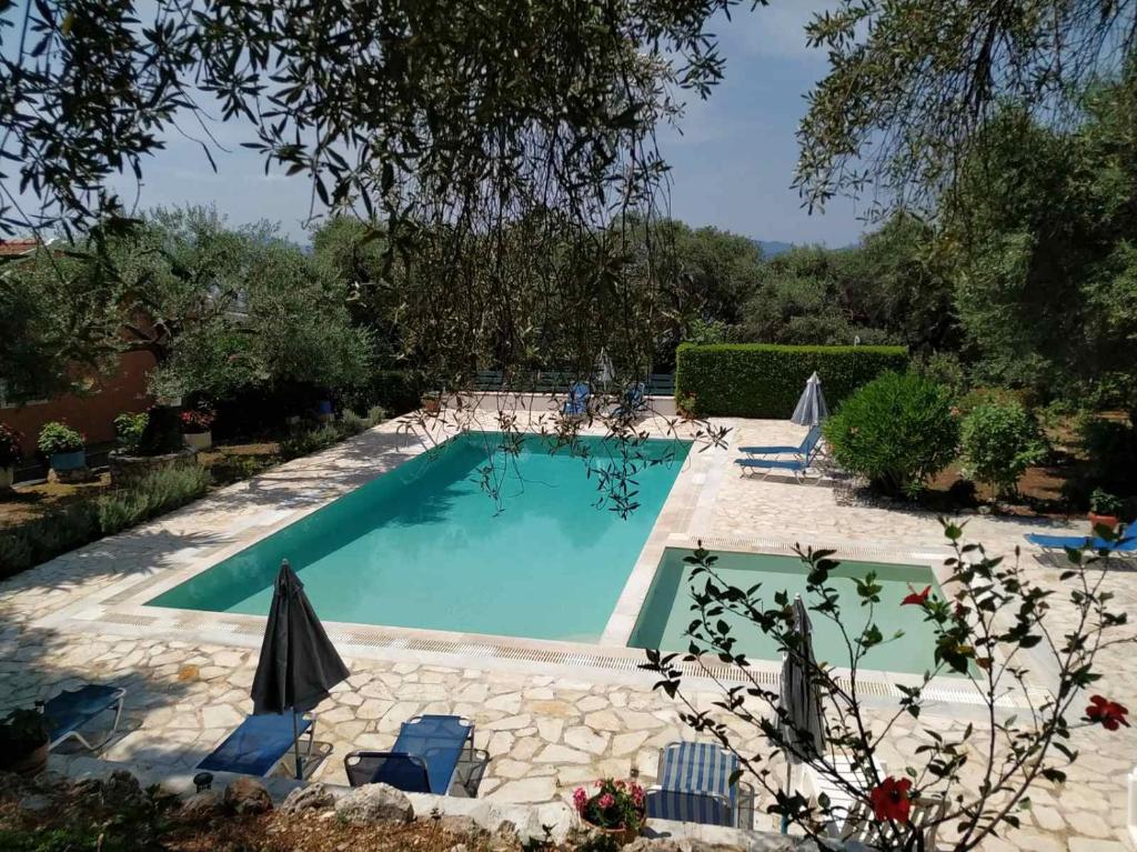 una piscina in un giardino con sedie e ombrellone di Villa Stefanos Apartments by Hotelius a Glyfa