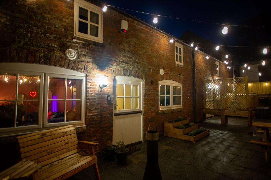 a brick building at night with a bench and lights at The Stables - Quirky one bed holiday home with wood fired hot tub in Rudston