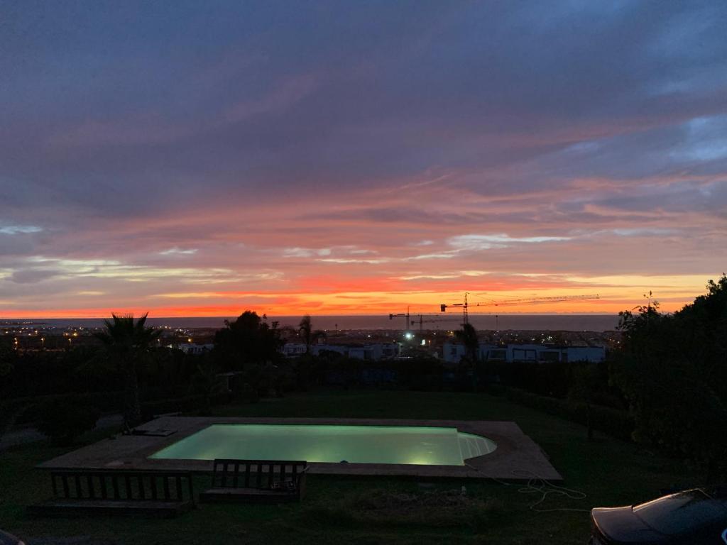 zachód słońca nad basenem na dziedzińcu w obiekcie Joumaya Blue Manoir w mieście Casablanca