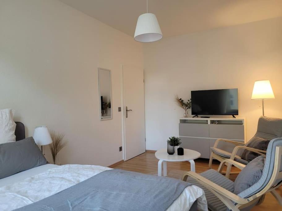 een slaapkamer met een bed en stoelen en een televisie bij Gemütliches helles Appartement in Dresden