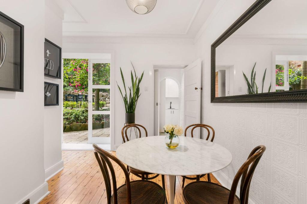 a white dining room with a table and chairs at Classic Art Deco in Sydney