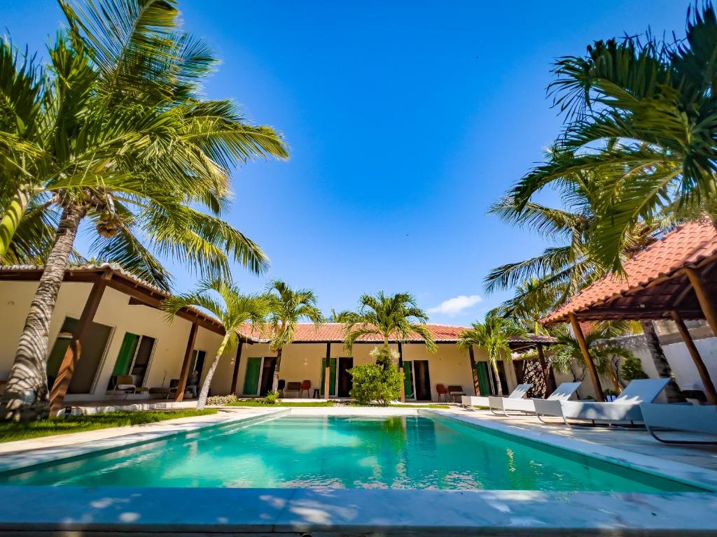 a swimming pool in front of a house with palm trees at Casa das Flores in Barra Grande