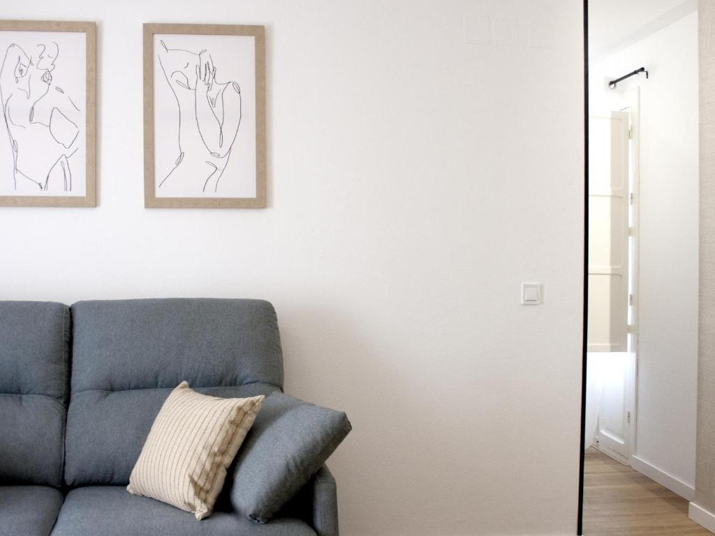 een woonkamer met een blauwe bank en twee tekeningen aan de muur bij BT Alfalfa Excelente Ubicación Ideal para parejas in Sevilla