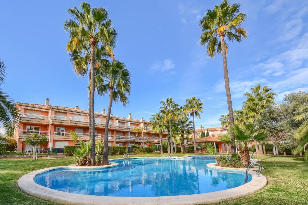 uma piscina de resort com palmeiras em frente a um edifício em Jardines de Gabriel em Xàbia