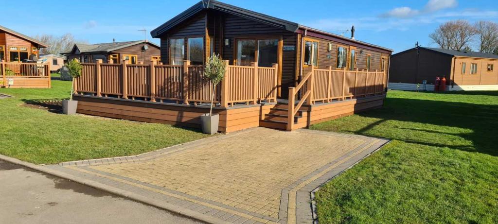 een groot houten huis met een veranda op het gras bij Little Gem Lodge with Hot Tub in Malton