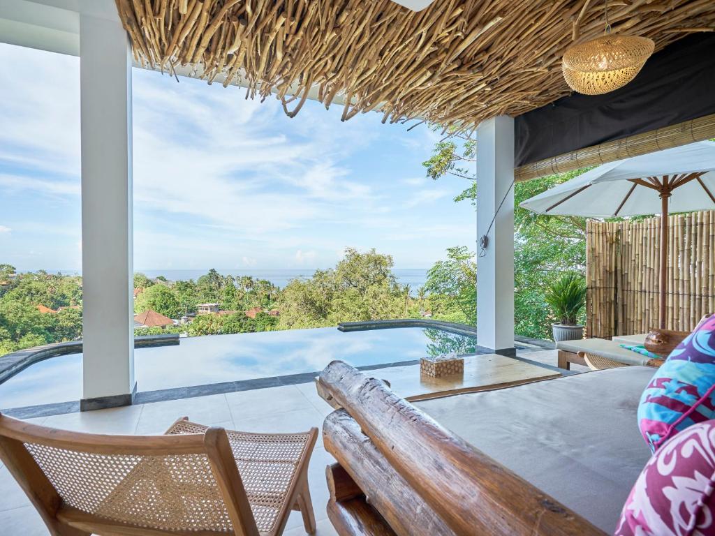 a patio with a table and chairs and a swimming pool at Villa Mimpi Tamarind in Amed