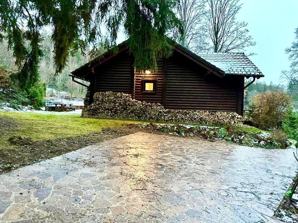 uma cabana de madeira com um passadiço de tijolos à frente. em Luxusní srub na Lipně em Lipno nad Vltavou