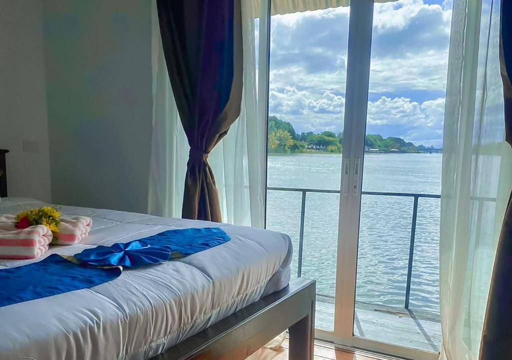 a bedroom with a large window with a view of the water at Tara Raft in Kanchanaburi City