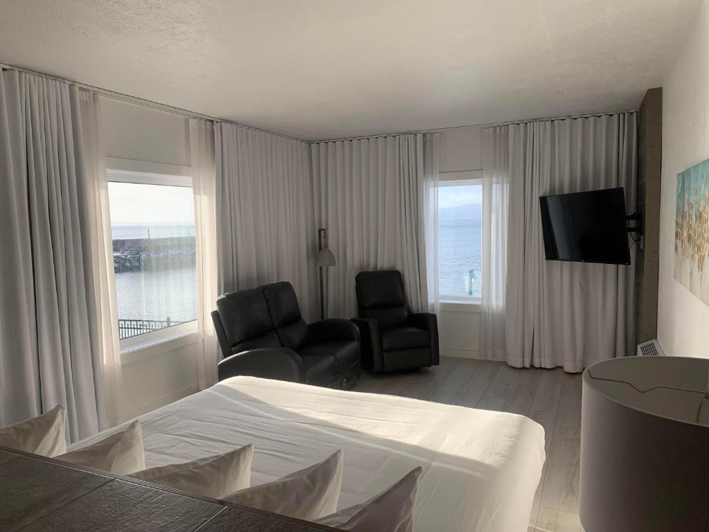 een hotelkamer met een bed, een stoel en een televisie bij Hôtel Sept-Îles in Sept-Îles