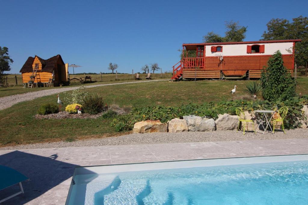 einen Hinterhof mit einem Haus und einer Scheune und einem Garten mit einem Pool in der Unterkunft Roulotte La Comtoise 