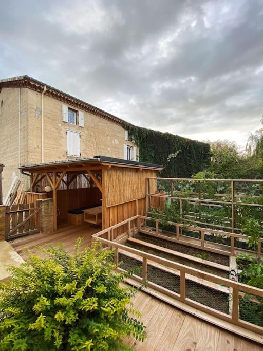 a house with a wooden deck with a building at Gîte : La vieille bâtisse. in La Baume-Cornillane