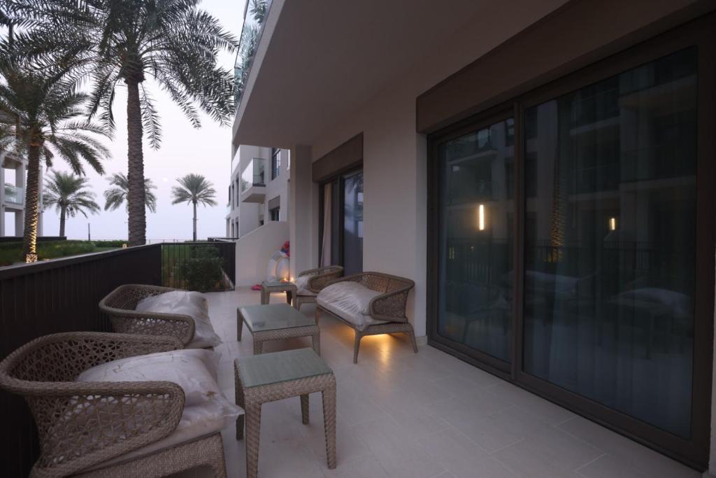 a balcony with chairs and tables and palm trees at Address Beach Fujairah sharm in Fujairah