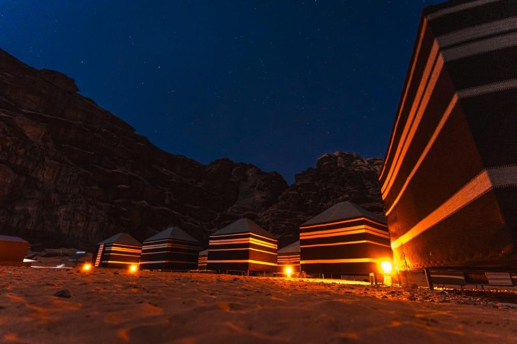 - une rangée de tentes sur la plage la nuit dans l'établissement Wadi rum secrets camp, à Wadi Rum