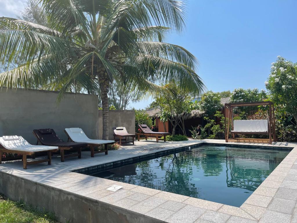 a swimming pool with chairs and a palm tree at maison vanilianadia in Nosy Be